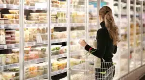 Woman shopping in front of refrigerated display cases using R290 refrigerants